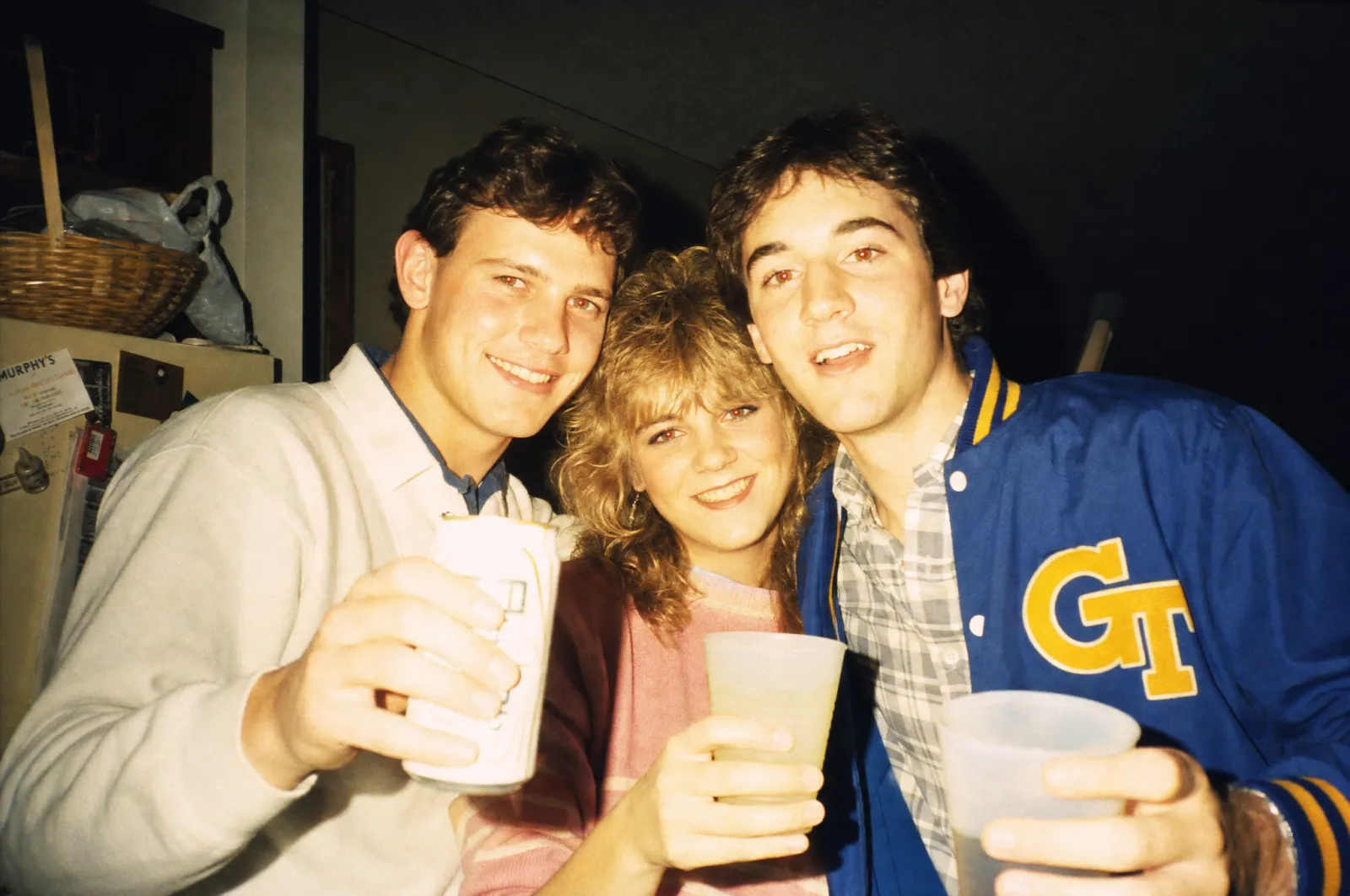 A 1986 kitchen-party snapshot generated from prompt 2: direct on-camera flash burning out the foreground, a hard shadow on the wall behind the group, red-eye and a warm Kodacolor cast