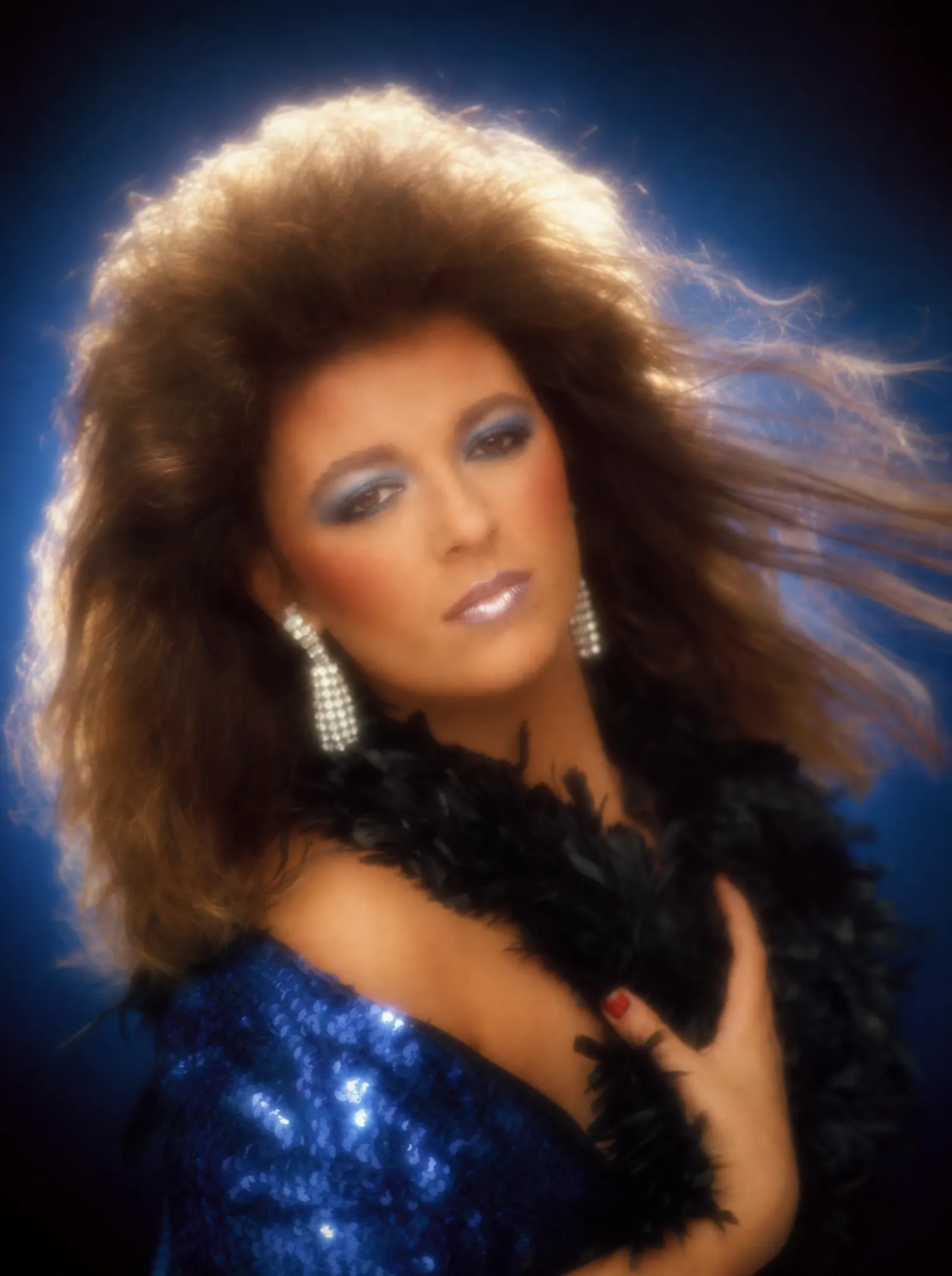A 1991 mall-studio glamour portrait generated from prompt 36: blue gradient backdrop, hair light halo, wind machine, feather boa, blue eyeshadow and heavy soft-focus diffusion